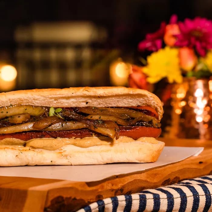 A recent post from The Burgerly’s Instagram — a loaded hot dog plated warm on a live-edge wood board.